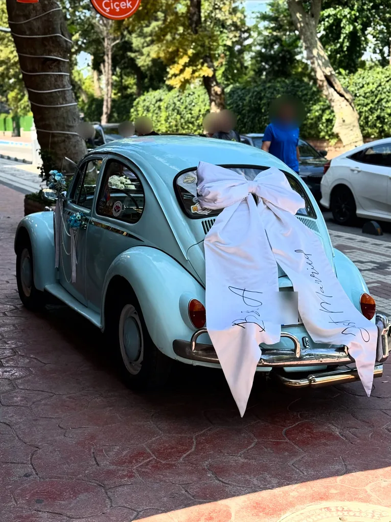 Arkasında büyük beyaz Just Married fiyonku olan açık mavi klasik Vosvos gelin arabası, Çark Çiçek mağazası önünde