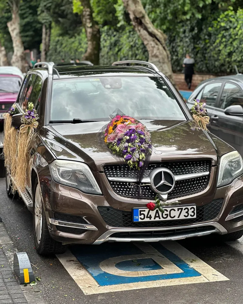 Kaputunda ayçiçekli ve mor lisyantuslu buket bulunan kahverengi SUV